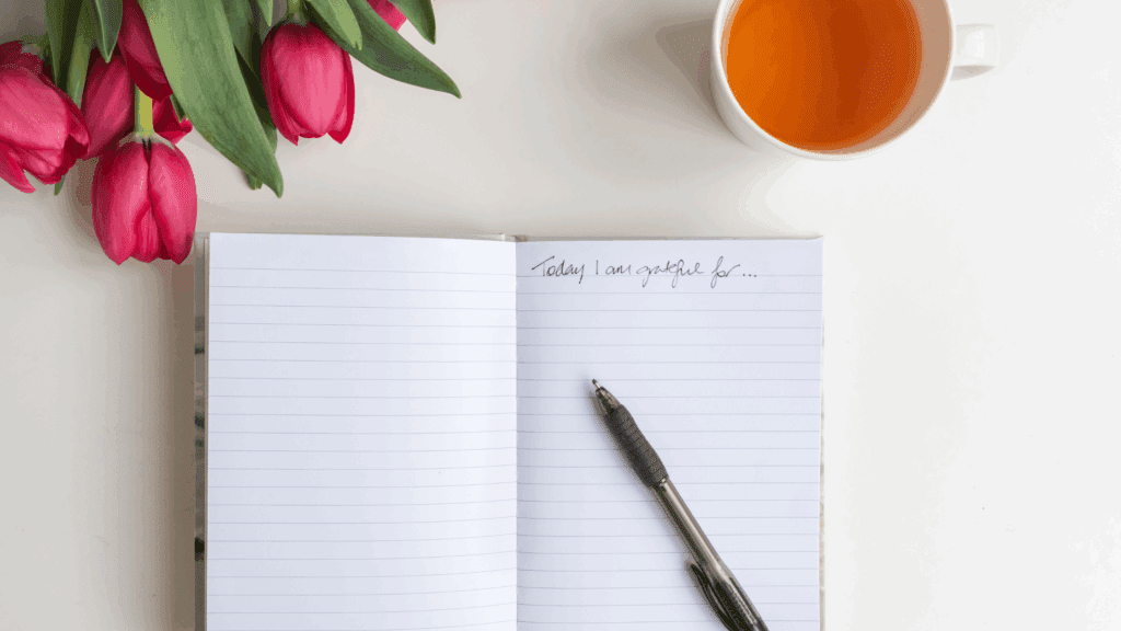 A morning scene: a tidy bedside table with a gratitude journal open, a pen, and a small plant—conveying daily ritual.