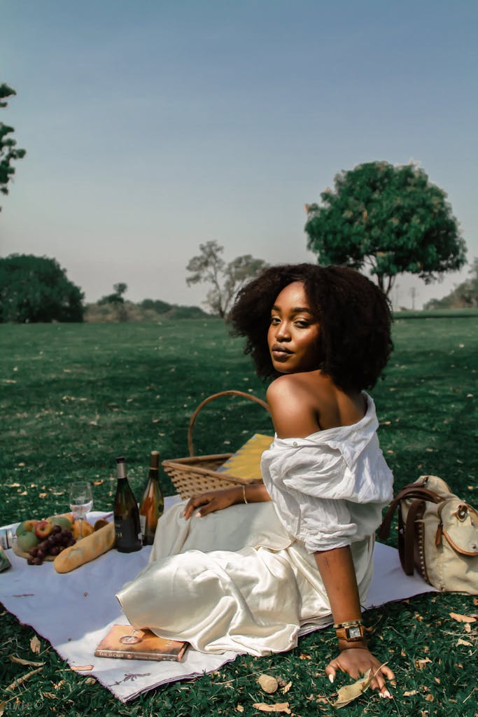 A woman enjoys a serene picnic on a sunny day with wine and fruit. Reinvent yourself after 35 and start building a life that truly