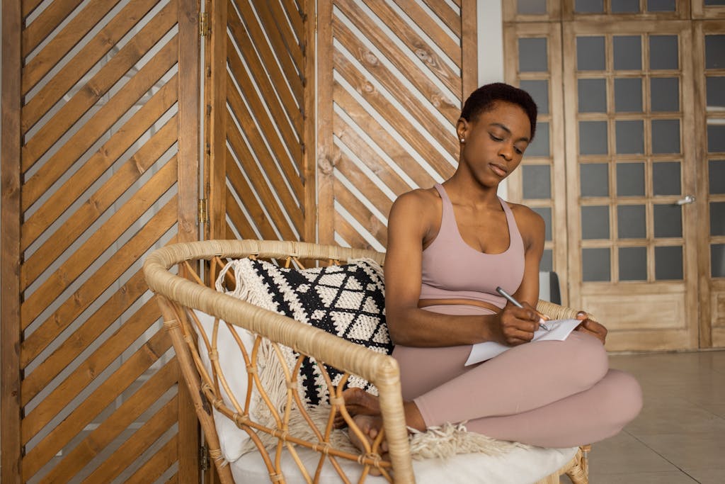 A woman sitting comfortably in a wicker chair writing in her journal or a notebook
