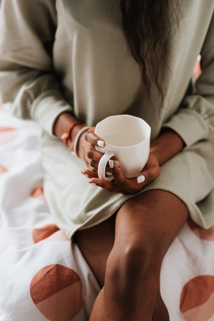 Close-up of a woman holding a tea cup while sitting comfortably indoors.