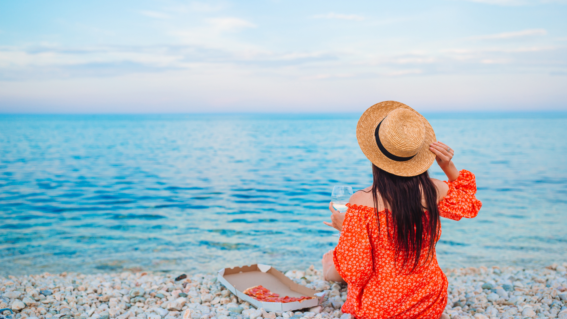 WOMAN SITTING ON SAND SIPPING WINE, EATING PIZZA, NOT LIVING ON AUTO PILOT