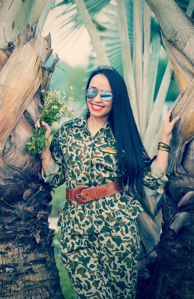 A woman in a camouflage outfit smiling and wearing Belt accessories that brings joy