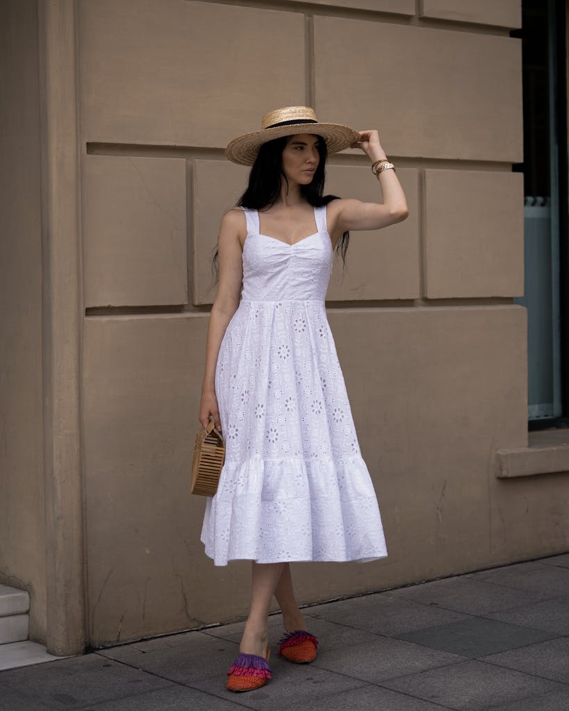 Stylish woman posing in a white summer dress and woven hat accessories that brings joy to outfit