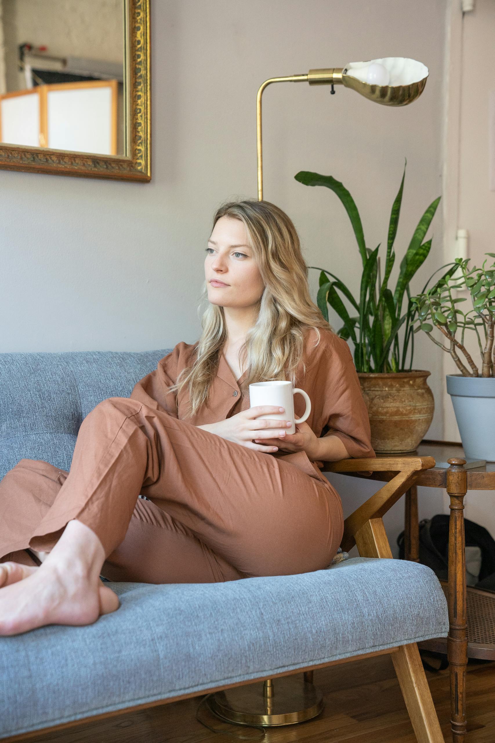 A woman looking uncertain but thoughtful, perhaps in a cozy living room sipping coffee.