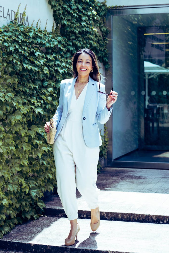 Confident woman in a blue blazer and white suit walking outside on a sunny day.
